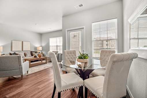 A modern living room with a glass table and white chairs.