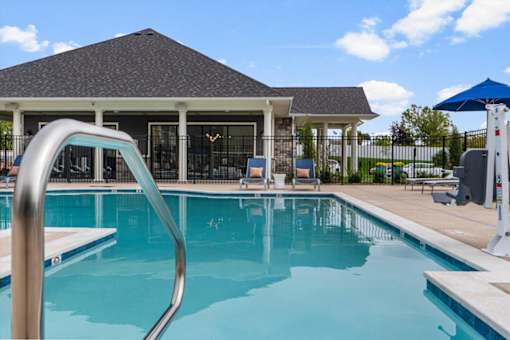 A swimming pool in front of a house with a slide.