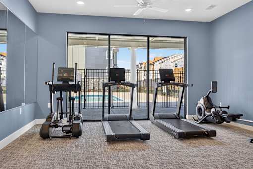 A home gym with a treadmill, elliptical trainer, and stationary bike.