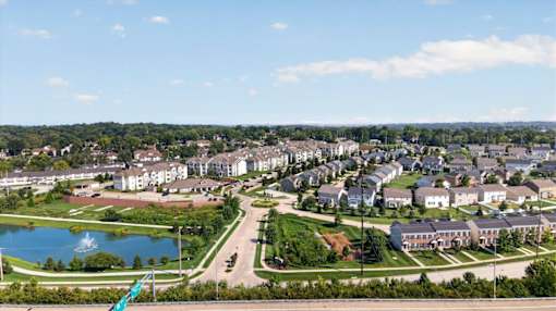 A view of a residential area with houses, a lake, and a green flag.
