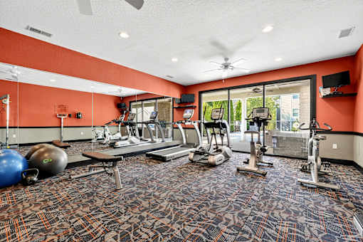 A gym with a variety of equipment including treadmills, weights, and exercise machines.