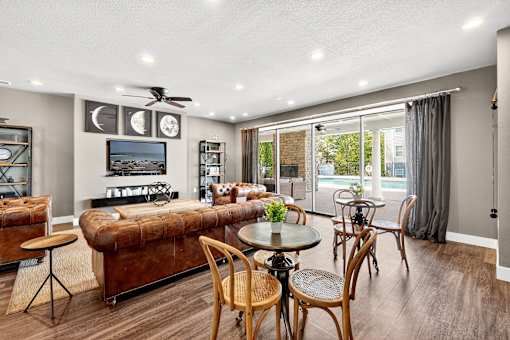 A living room with a brown couch, a television, and a ceiling fan.