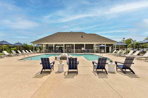 A large outdoor swimming pool area with sun loungers and a building in the background.