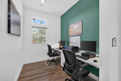 A room with two chairs and two desks with computers.