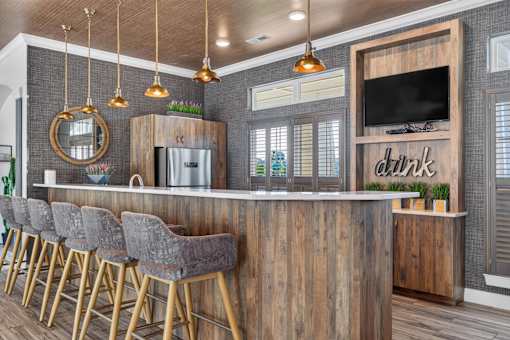 A bar area with a wooden counter and grey chairs.