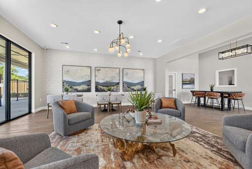 A living room with a glass table and grey couches.