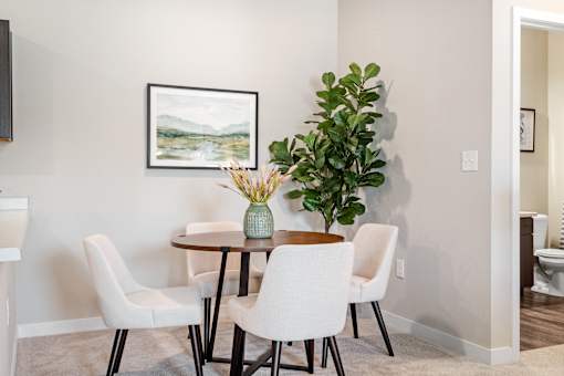 A dining room with a table, chairs, and a painting on the wall.