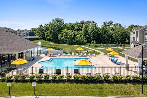 A large swimming pool surrounded by yellow umbrellas and blue chairs at Aventura at Wentzville I & II Apartments, Wentzville, 63385