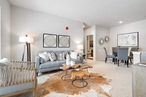 A living room with a grey couch, a brown cowhide rug, and a wooden coffee table.