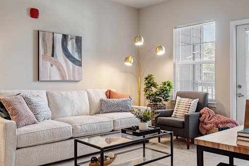 A living room with a white couch and a painting on the wall at Aventura at Wentzville I & II Apartments, Wentzville, MO