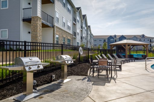 an outdoor patio with tables and barbecue grills at The Edison at Blue Springs, Blue Springs, MO