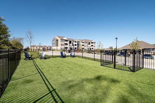 A grassy area in front of a building with a black fence.