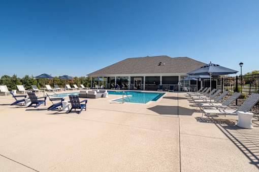 A pool area with sun loungers and a building in the background.
