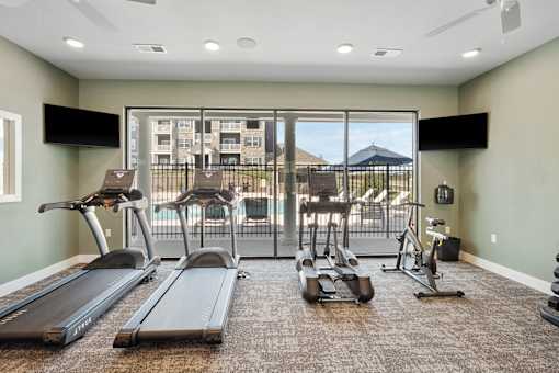 A gym with treadmills, elliptical machines, and a television.