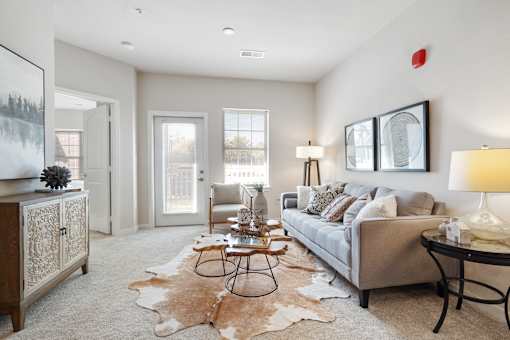A living room with a grey couch, a black table, and a cowhide rug.