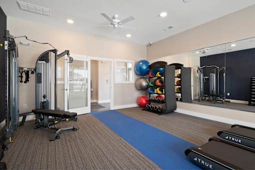 A gym with a variety of equipment including treadmills, weights, and a mirror at Aventura at Wentzville I & II Apartments, Wentzville, 63385