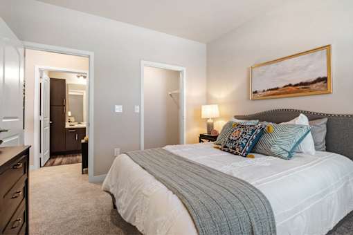 A bedroom with a large bed and a painting on the wall at Aventura at Wentzville I & II Apartments, Missouri