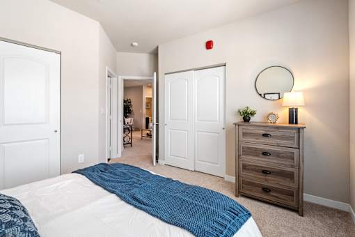 A bedroom with a bed, dresser, and mirror at Aventura at Wentzville I & II Apartments, Wentzville, MO, 63385