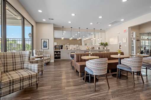 A well-lit, modern living room with a dining area and a kitchen in the background at Aventura at Wentzville I & II Apartments, Wentzville