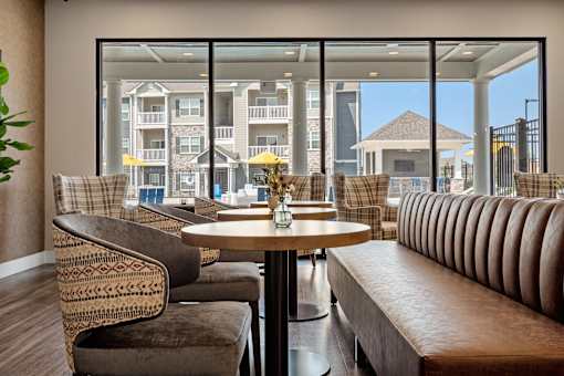 A round table with a vase of flowers on it sits in front of a large window at Aventura at Wentzville I & II Apartments, Wentzville, MO