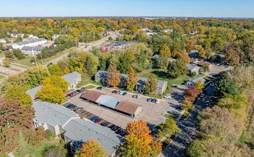 An aerial view of a parking lot surrounded by trees with autumn foliage.