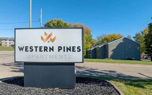 A sign for Western Pines Apartments is displayed in front of a building.