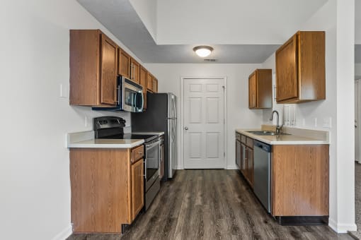 a kitchen with wooden cabinets and stainless steel appliances and a door