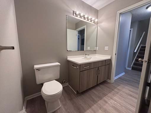 A bathroom with a toilet, sink, and mirror.