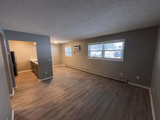 A room with a grey wall and a window with a view of cars and trees outside.