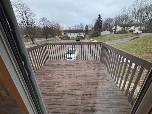 A view from a deck looking out at a car and houses.