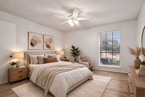 A bedroom with a large bed, a ceiling fan, and a window with blinds.