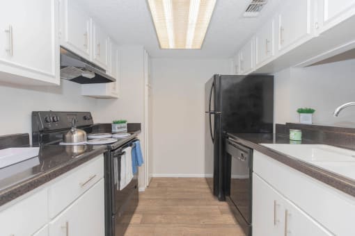 a kitchen with white cabinets and a black refrigerator at The Escapade, San Antonio, Texas
