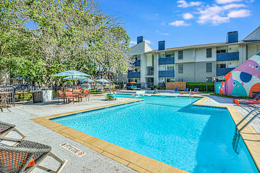 a swimming pool with an apartment building in the background at Peaks at Northwest Hills Apartments, Austin