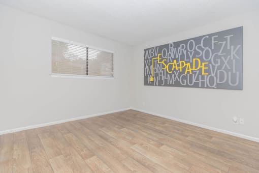 an empty room with wood floors and a window at The Escapade, San Antonio