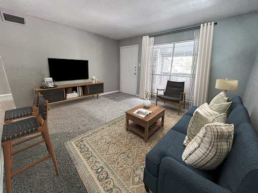 A living room with a blue couch, a wooden chair, a coffee table, and a television.