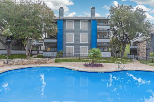 a large swimming pool with an apartment building in the background at The Escapade, San Antonio, 78216