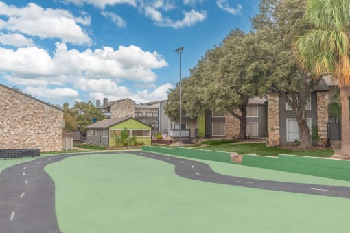 a green court in front of a building with apartments in the background at The Escapade, San Antonio, 78216