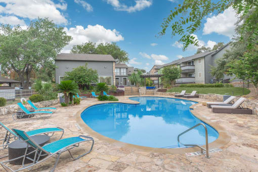 a swimming pool with chairs and a house in the background stock photography at The Escapade, San Antonio, 78216