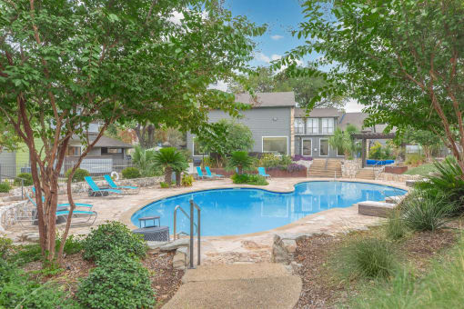 a swimming pool with trees and chairs around it at The Escapade, San Antonio, Texas