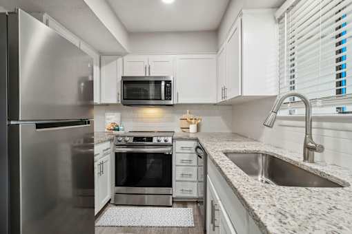 large kitchen with white cabinets, granite countertops and stainless steel appliances at The Escapade, San Antonio, TX