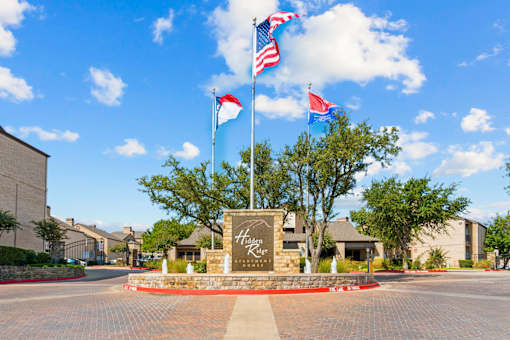 The image shows a sign that says "Highland Ridge" in front of a building with multiple flags flying in the background.