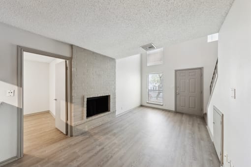 the living room and dining room of an apartment with a fireplace