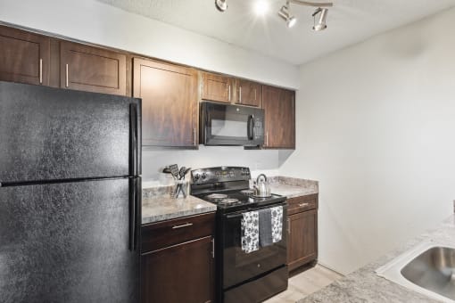 an apartment kitchen with black appliances and wood cabinets