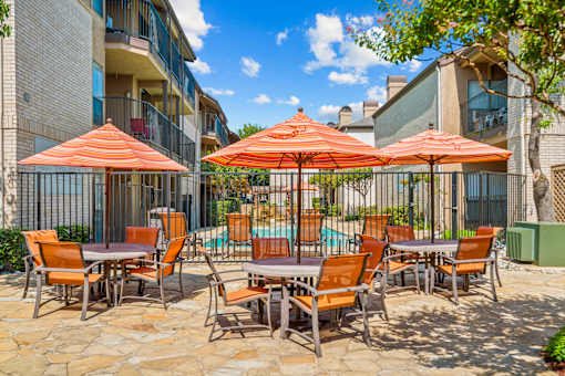 A patio with orange chairs and umbrellas.