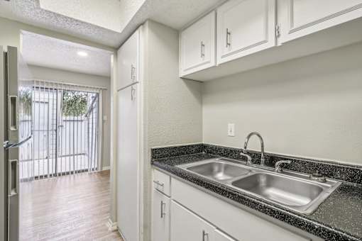a kitchen with white cabinets and a sink and a window at The Escapade, San Antonio, Texas