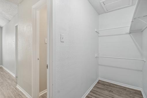 A walk-in closet of our A7 apartment The Escapade with white walls and wood flooring at The Escapade, San Antonio, 78216
