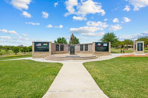 A monument surrounded by plaques is in the middle of a grassy area.