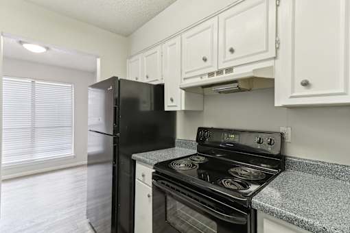 The Escapade apartment kitchen with black stove and refrigerator at The Escapade, San Antonio, Texas