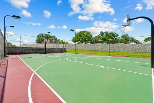 A basketball court with a red and green surface and a basketball hoop.