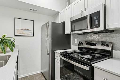 A black stove and microwave in a white kitchen.